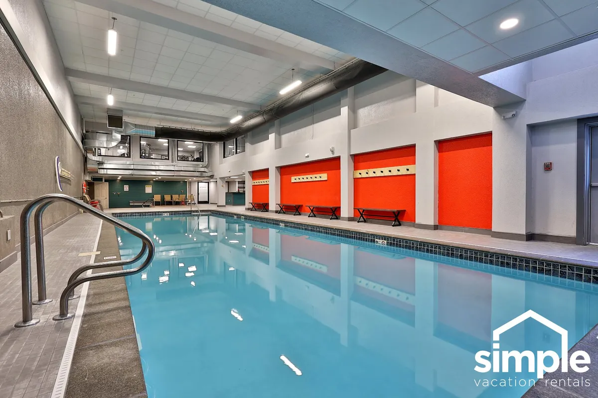 This image features an inviting indoor swimming pool with colorful accent walls and benches lining the poolside. The serene atmosphere suggests a relaxing environment ideal for unwinding after a day of adventure.