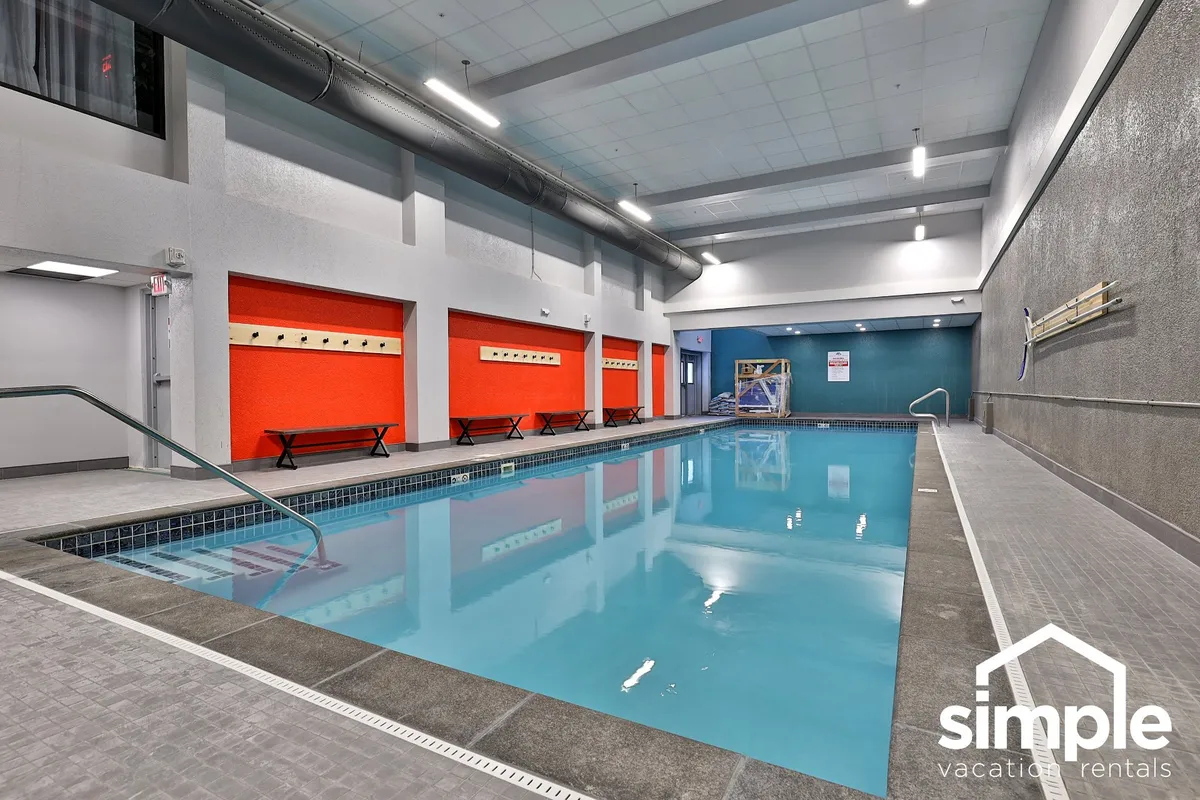 A lively indoor swimming pool surrounded by colorful wall accents and benches, capturing a cheerful mood ideal for après-ski relaxation. The vibrant setting suggests a space to unwind after a day on the mountain.