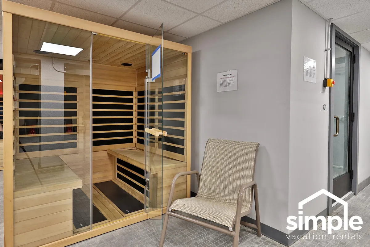 A tranquil sauna with wooden interiors and a comfortable lounge chair. The soft lighting and minimal decor create a peaceful setting for post-workout relaxation or a serene wellness routine.