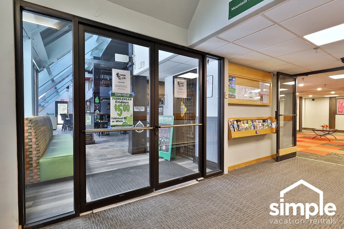 Depicts the inviting entryway and common area of the property, complete with glass doors, a comfortable seating area, and an information display. The bright, welcoming environment suggests a transition point before guests head out to enjoy local nightlife or gather information about nearby entertainment.