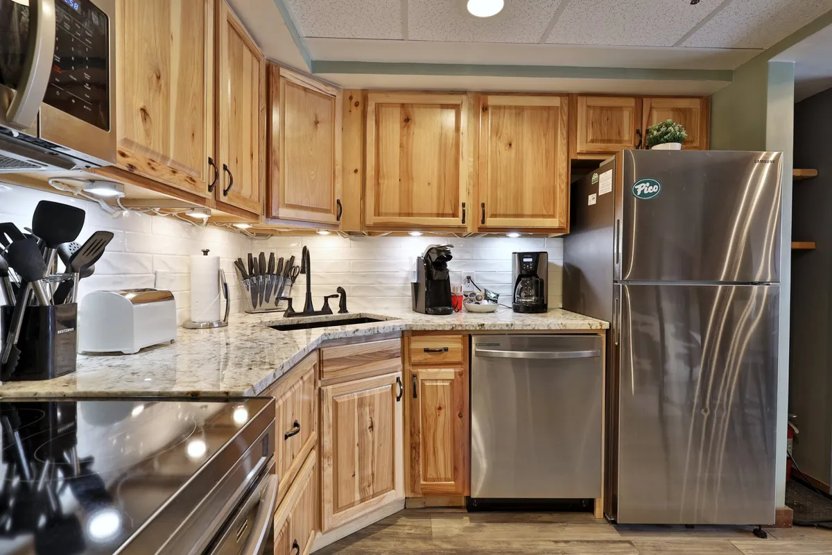A cozy kitchen featuring granite countertops, wooden cabinets, and stainless steel appliances. A coffee maker is visible, and the layout feels welcoming and practical—ideal for both cooking and socializing.