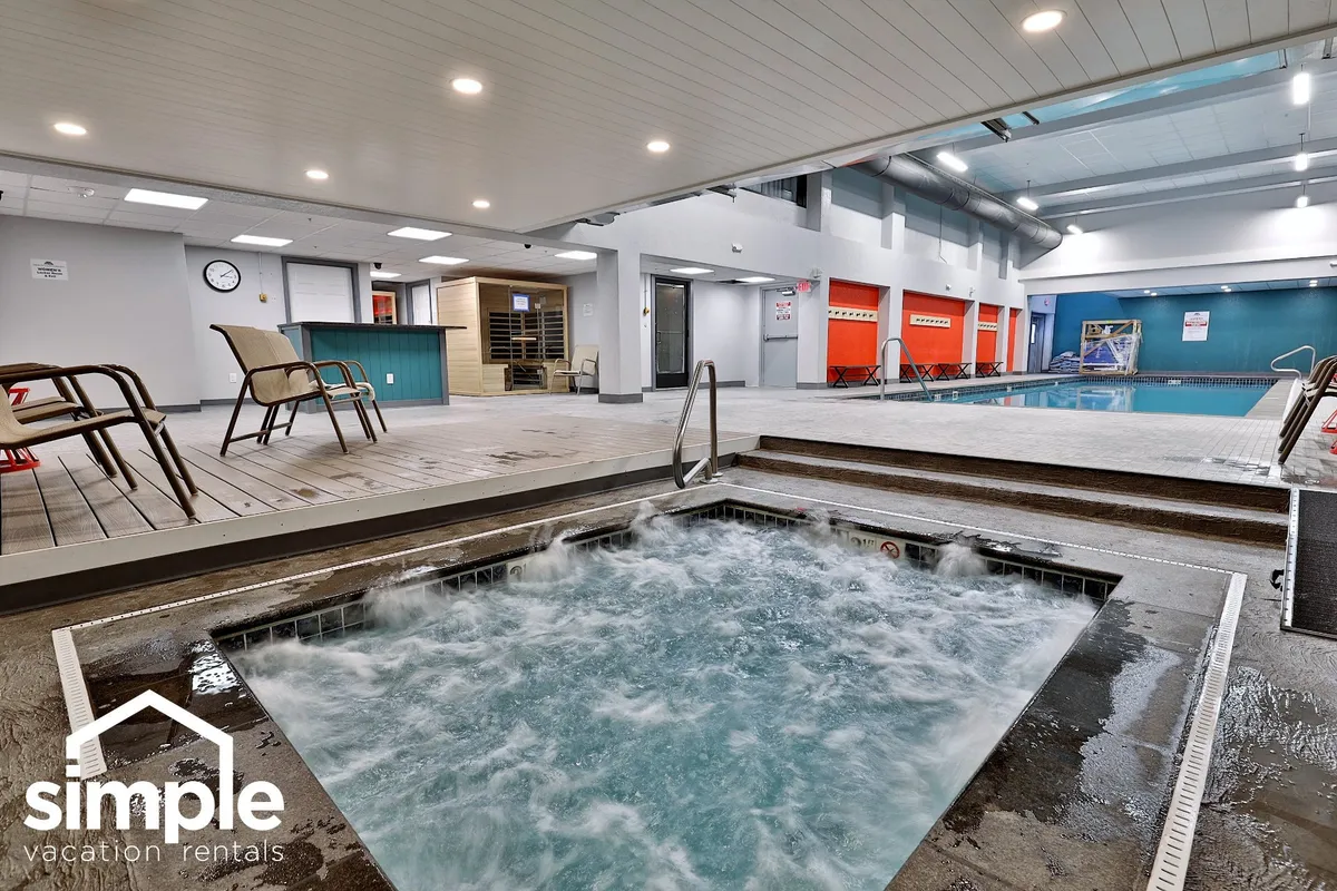 This interior shot captures a tranquil wellness space with a hot tub, glimpses of an indoor pool, and comfortable lounge chairs set in a serene environment. The soft lighting and layout suggest a peaceful place to unwind and socialize.