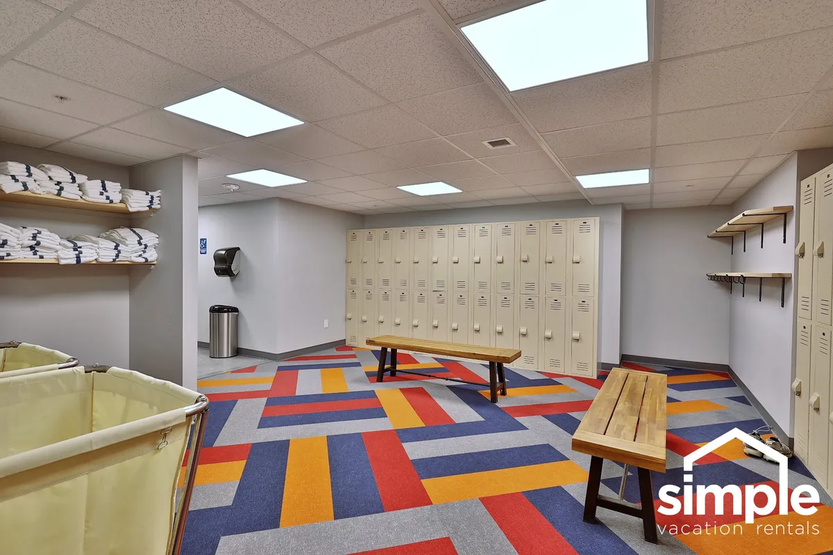 A practical, inviting locker room with colorful carpet, benches, and fresh towels. The scene suggests preparation for or relaxation after using amenities such as the pool, gym, or outdoor activities.
