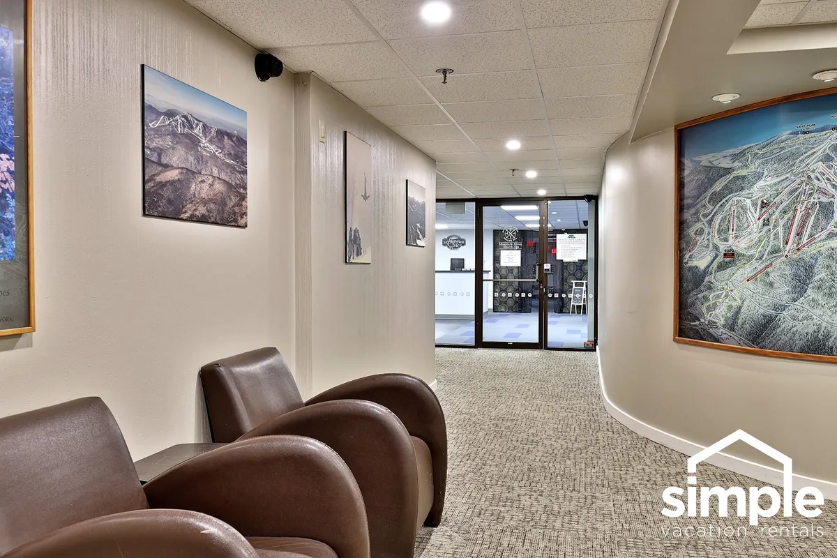 A calm and inviting lobby area featuring two brown chairs, a small table, wall art, and an entrance to another room. The setup suggests a welcoming common space where guests might wait, relax, or prepare for their next outing.