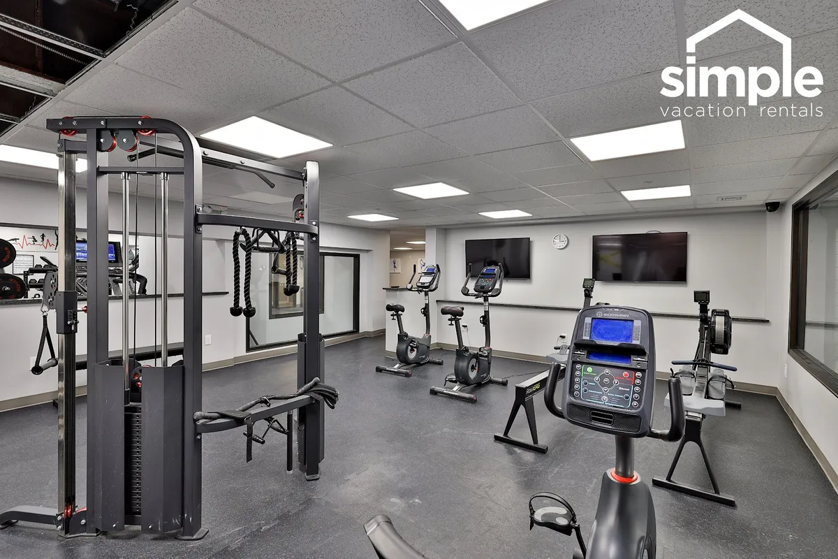 A bright, invigorating fitness center with modern gym equipment, including stationary bikes and treadmills, large mirrors, and televisions. The space is designed for active guests and supports a variety of fitness activities.